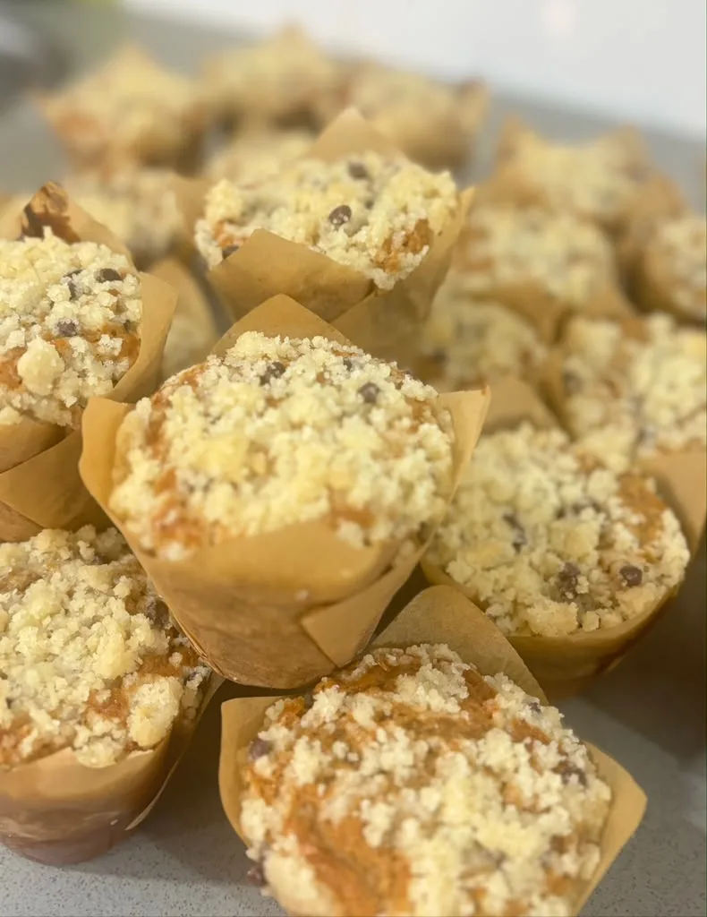 Close-up of crumb-topped spelt muffins in brown paper wrappers